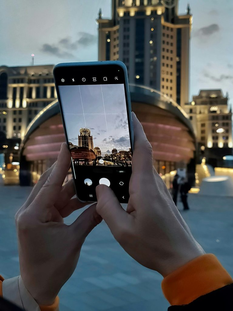 a woman holds a cell phone in her hands and photographs a night city