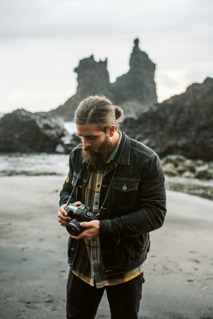 Bearded photographer standing near sea