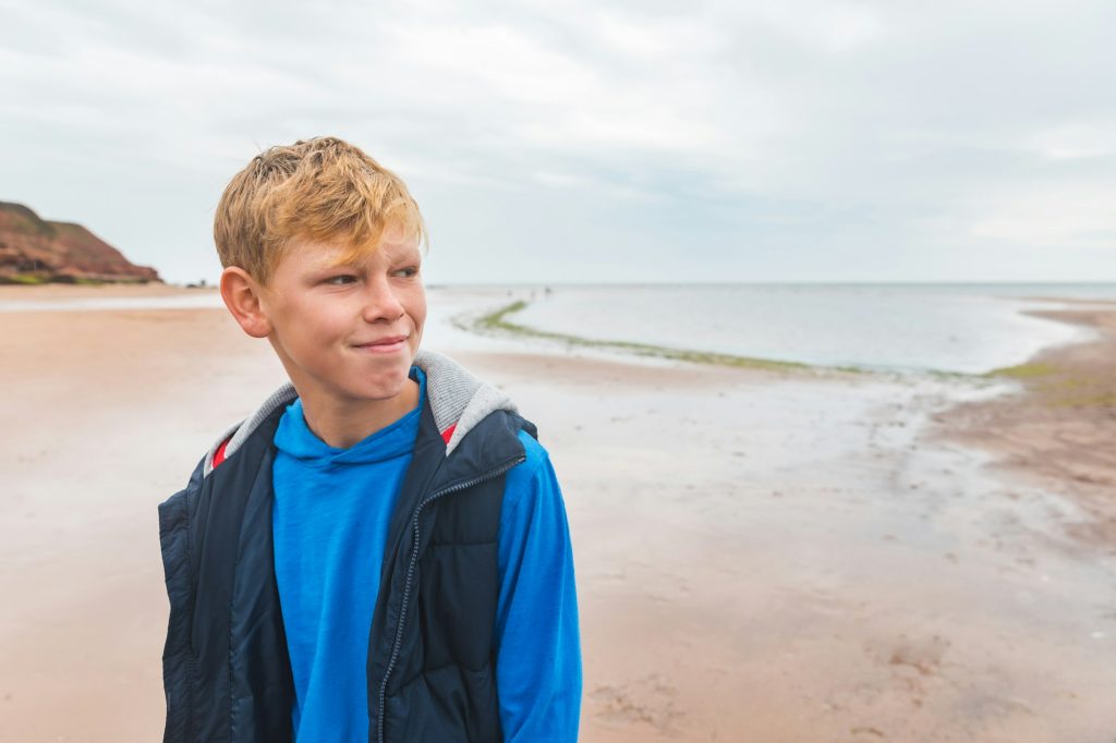 Boy alone portrait on the beach on cloudy day