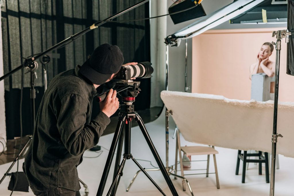 Cameraman filming beautiful woman in photo studio