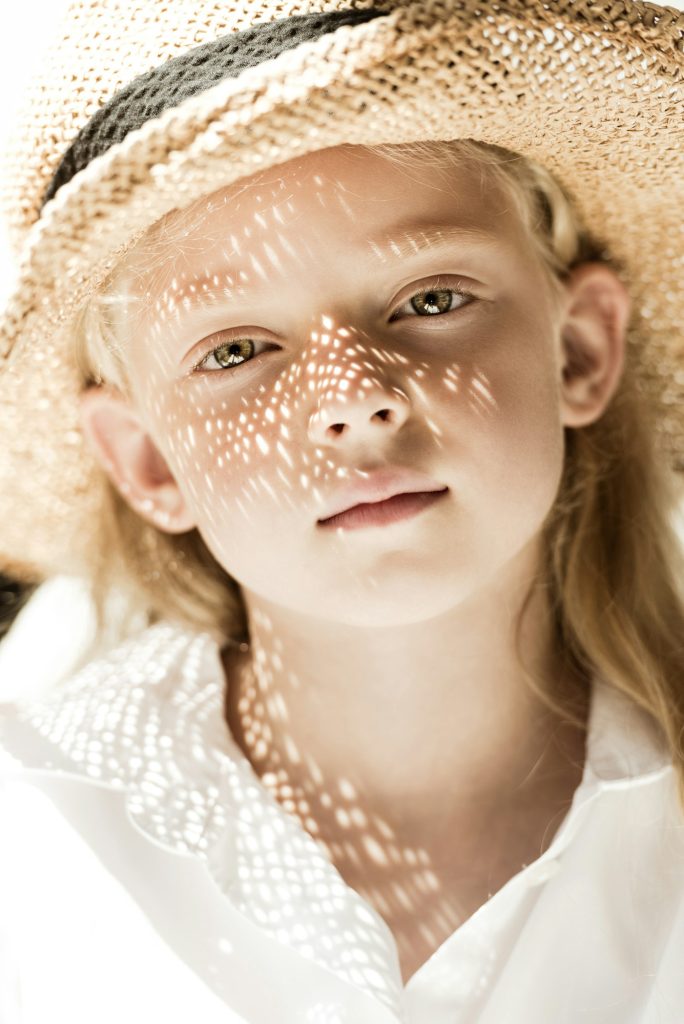 close-up portrait of adorable child in wicker hat looking at camera