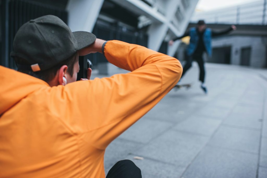 close-up shot of man taking photo of skateboarder doing trick