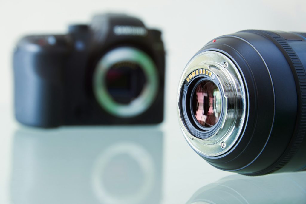 Closeup Of DSLR Photo Camera And Still Lens On Desk