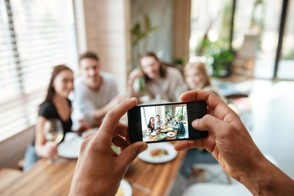 Closeup of man taking pictures of friends with cell phone