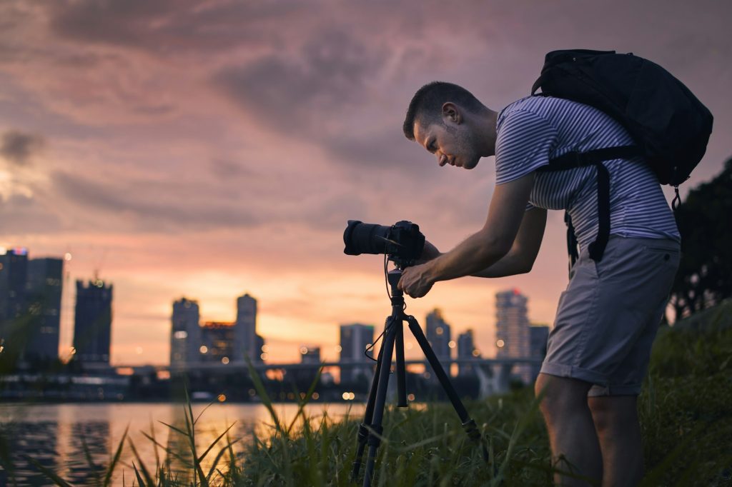 Concentrated photographer with camera on tripod at sunset