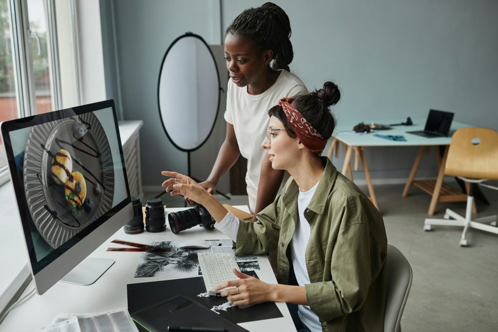 Female Photographers Discussing Photo on Screen