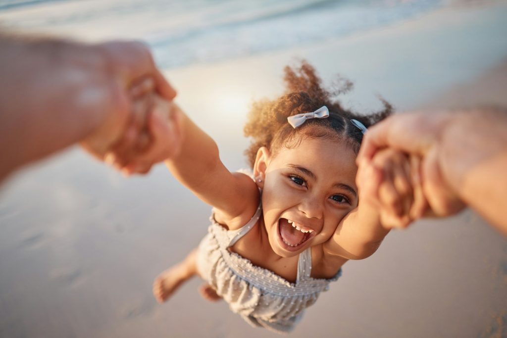 Girl child, spin and pov by ocean, portrait and smile for game, holding hands or speed in summer. Y