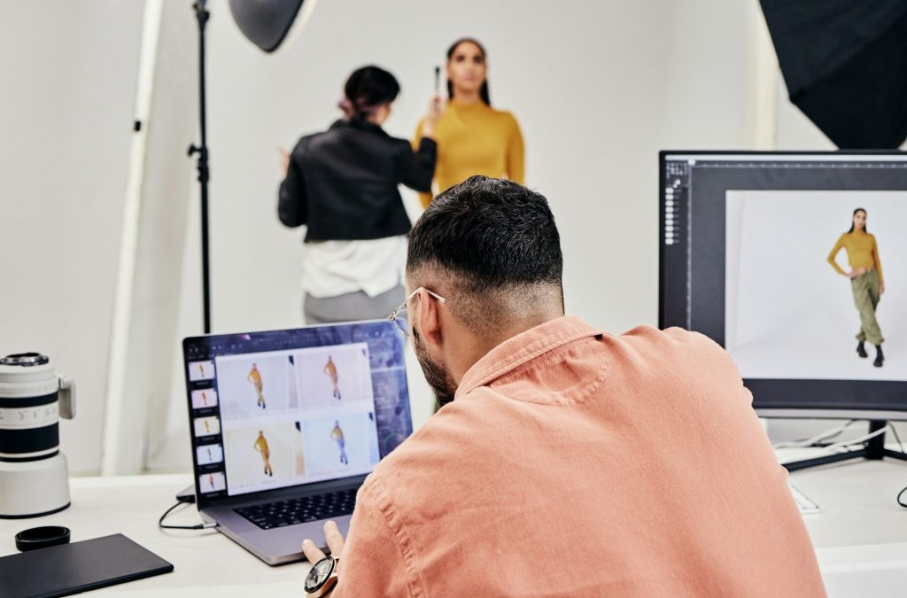 Laptop, photography editor and model in studio with photographer and shooting fashion design magazi