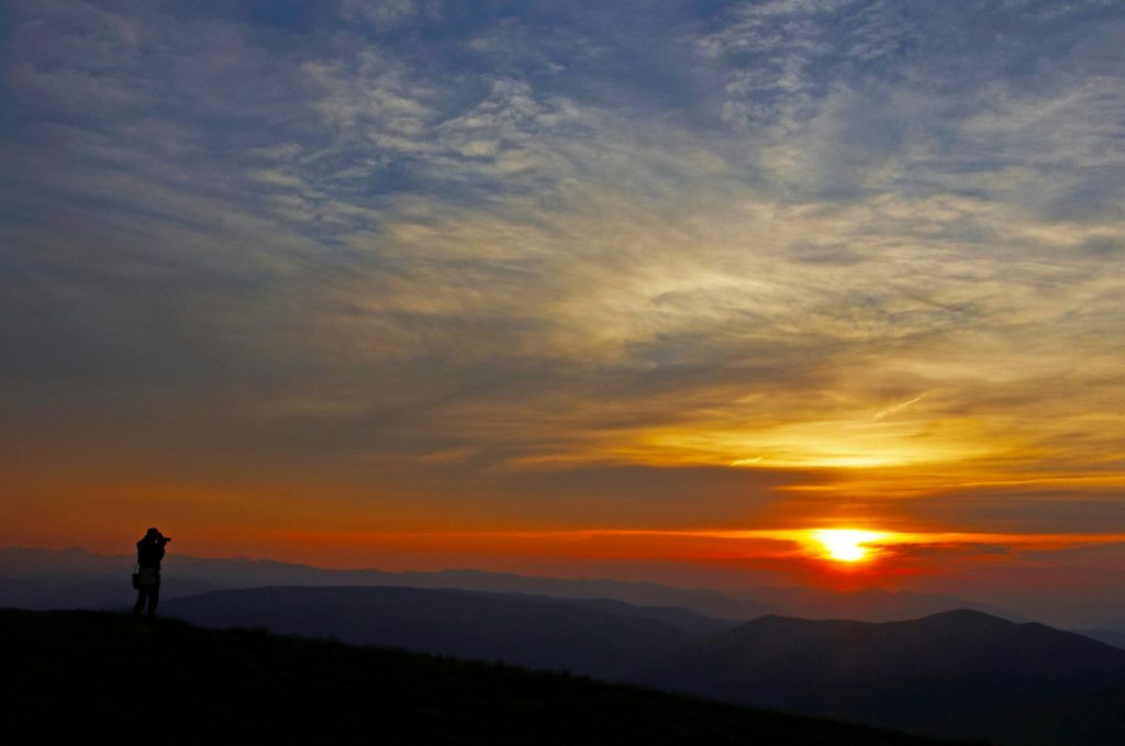 lonely traveler tourist in high mountains. photograph take photo of sunrise or sunset in trip