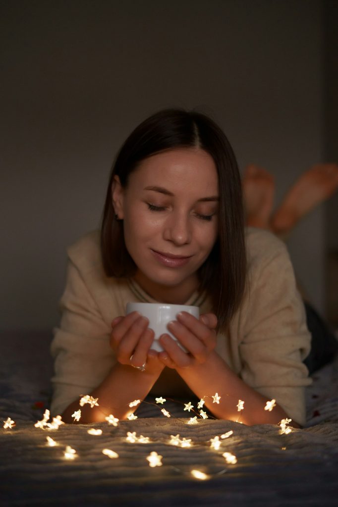 Lovely woman lying on bed with glowing lights