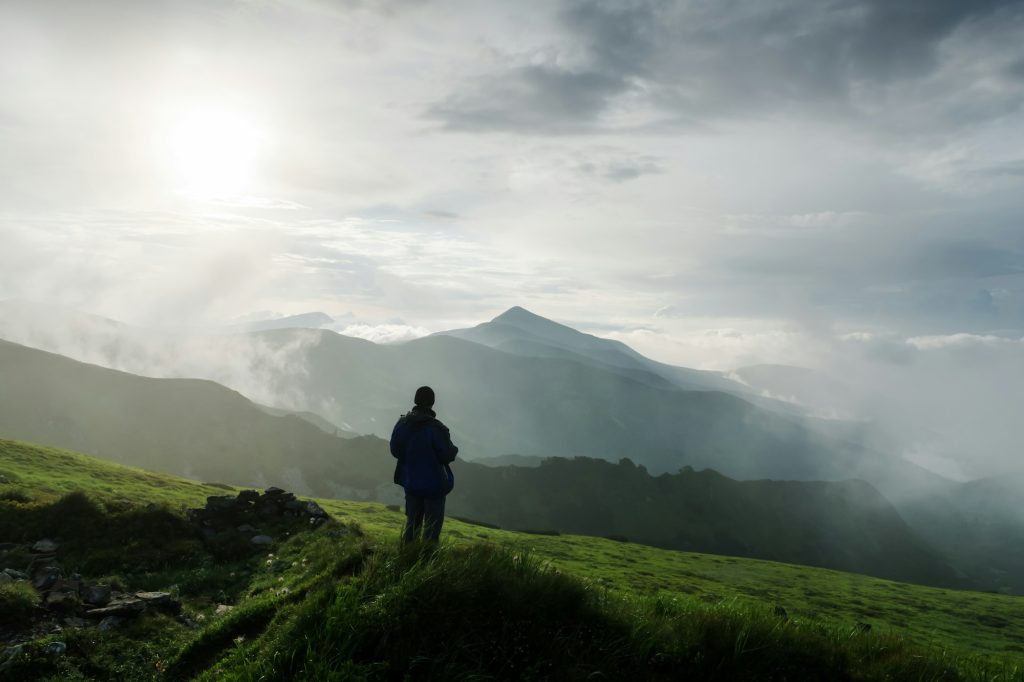 Man silhouette on cloudy mountains