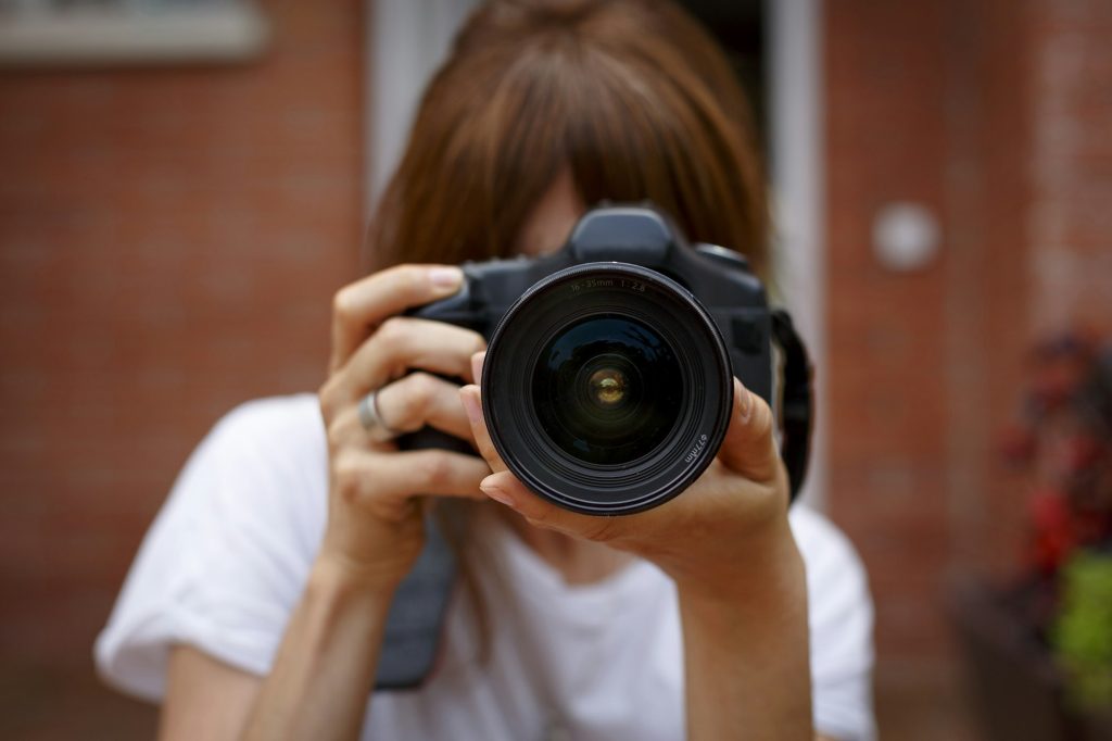 Mid adult woman using digital camera, face obscured