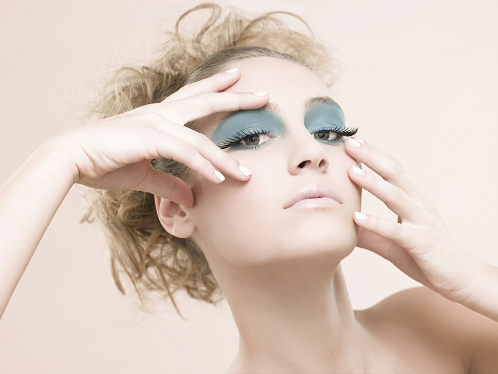 Model with bold blue eyelashes striking a pose.