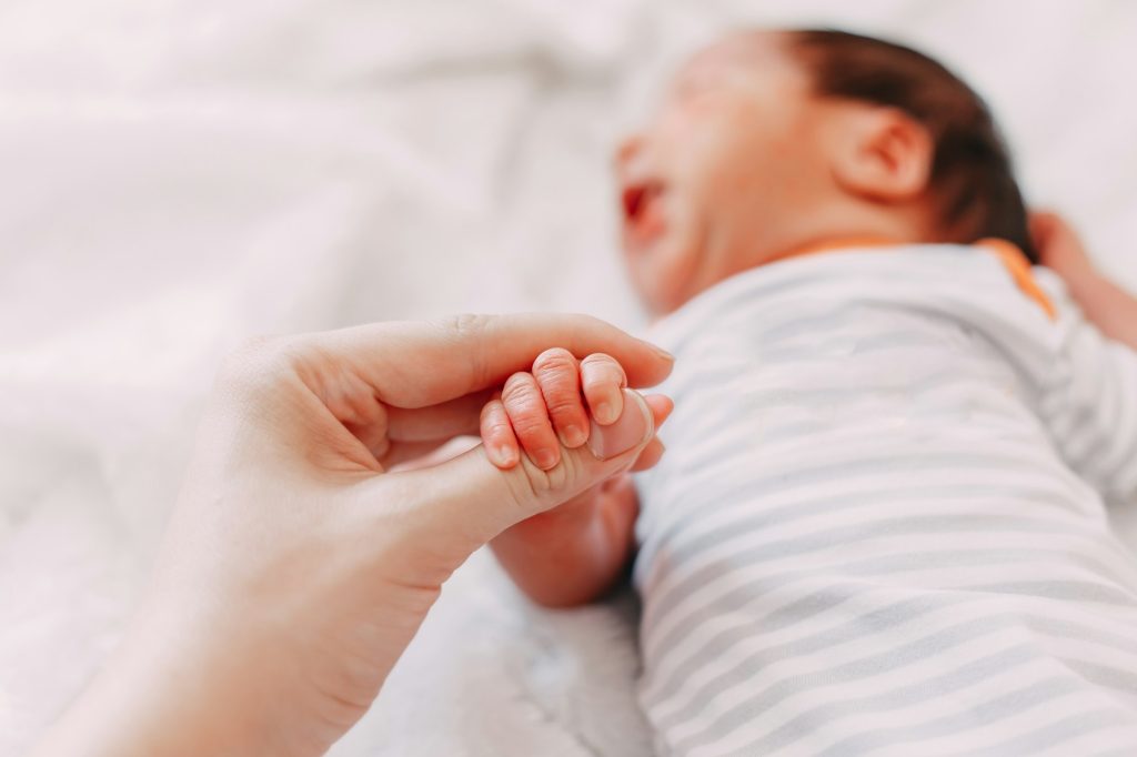 newborn baby holding mother's finger