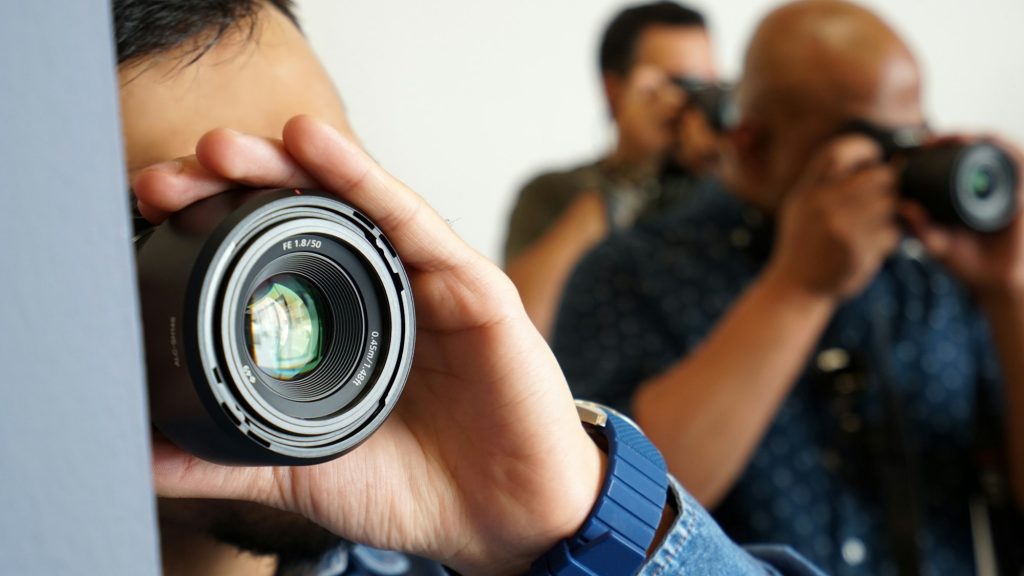 Photography is my hobby. Three men holding cameras and taking pictures.