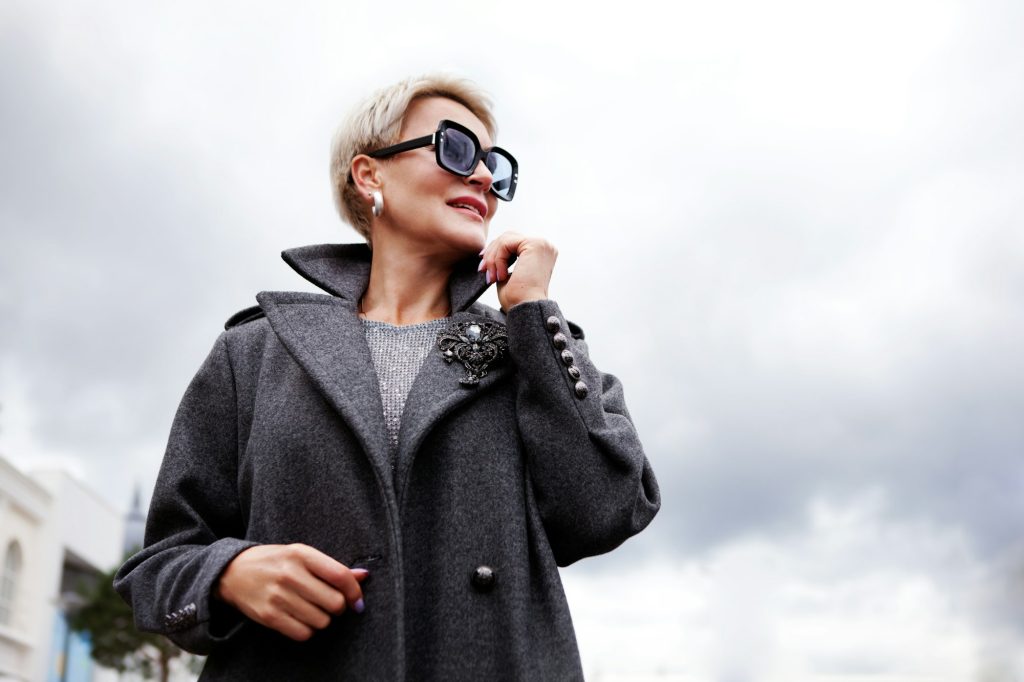 Portrait attractive female model on cloudy sky background. Modern stylish woman with short hair