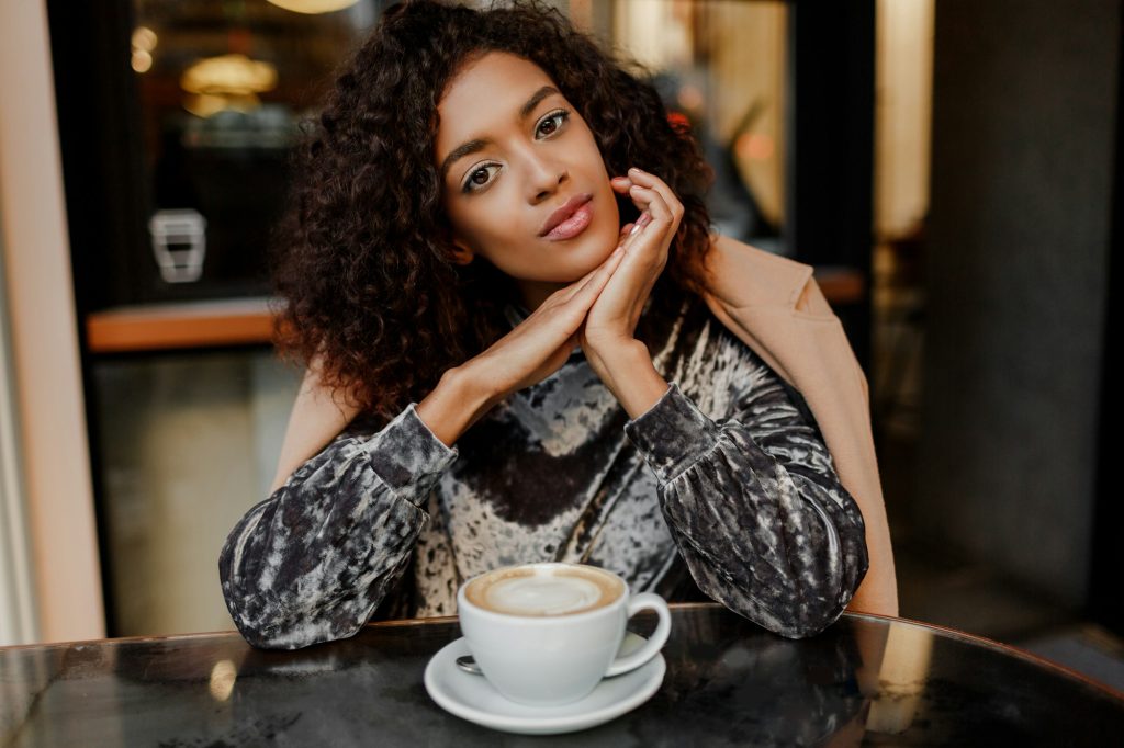 Portrait of happy carefree black woman enjoying coffee break in Paris.