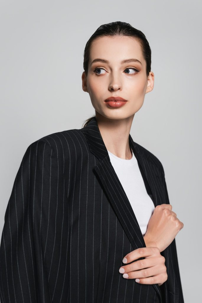 Portrait of woman in t-shirt and striped jacket looking away isolated on grey