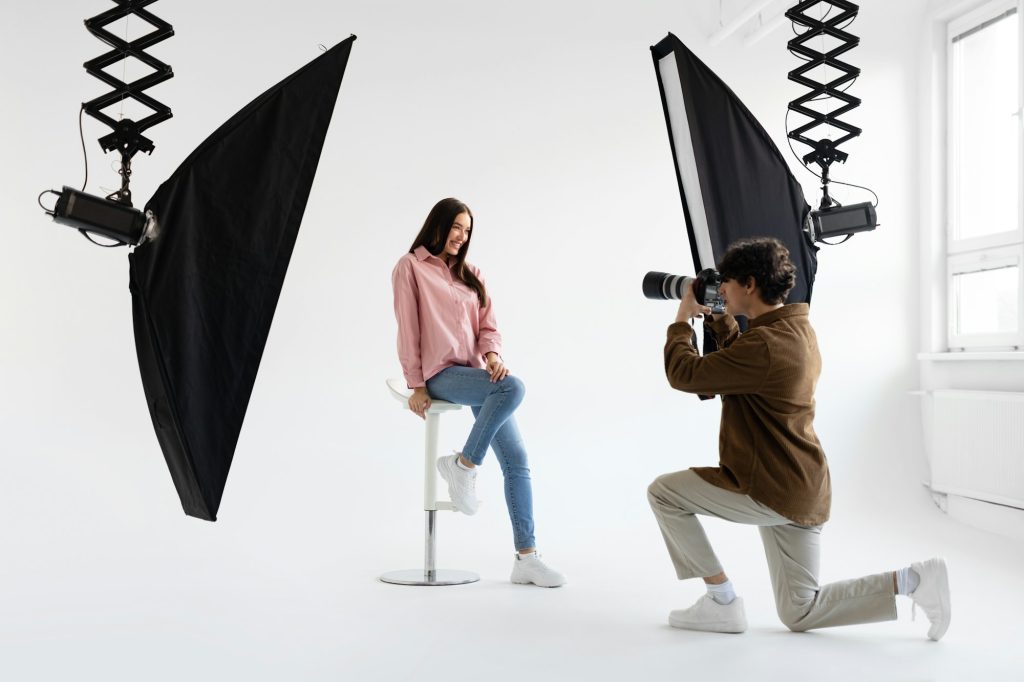 Professional photographer taking picture of young woman, having photoshoot in studio with lighting