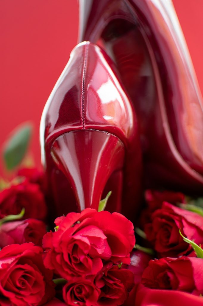 Red high heel shoes with roses on satin background