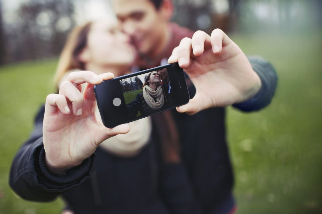 Romantic teenage couple taking self portrait with cell phone