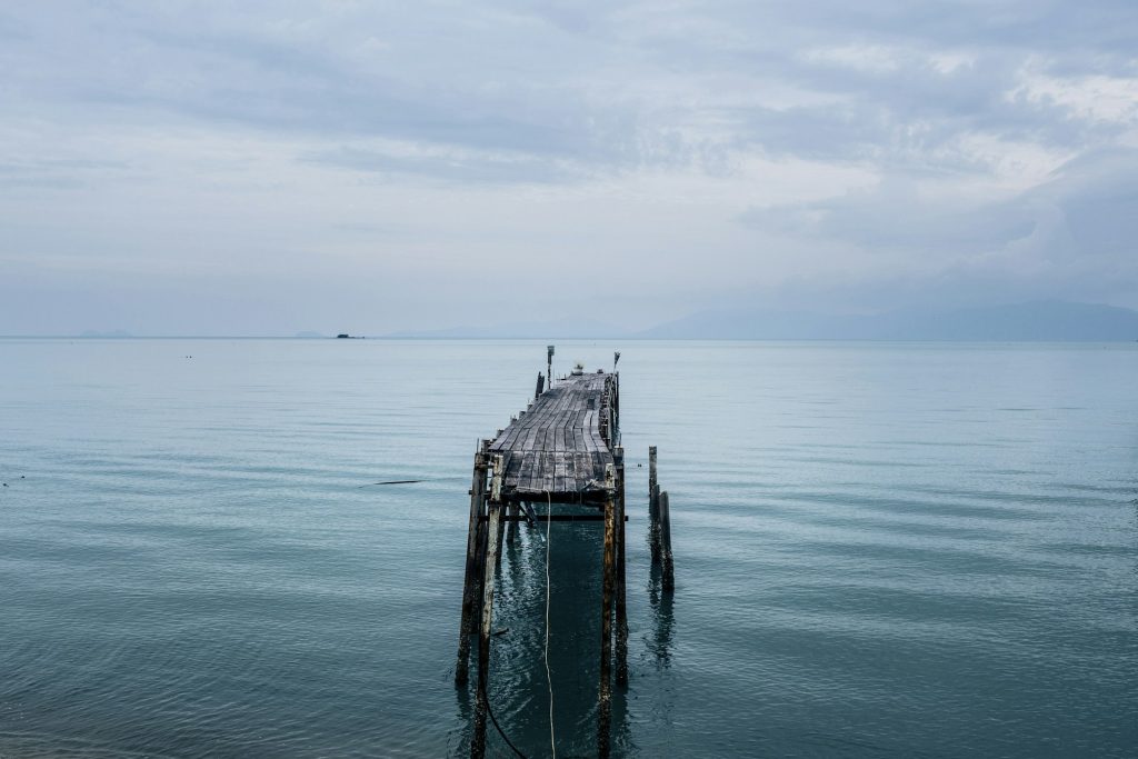 Seascape with old wooden jetty under a cloudy sky.