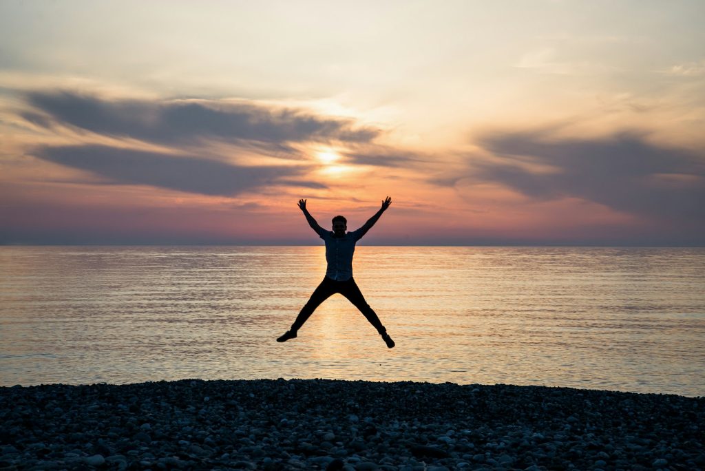 Silhouette of jumping man on sunrise background