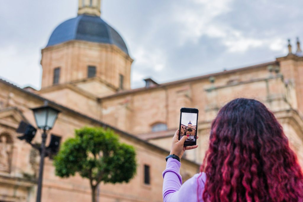 Smartphone tourist trip photography. Mid aged Latin woman. Iglesia de la Purisima, Salamanca