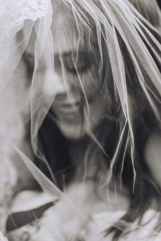 Smiling bride under veil on wedding day in black and white