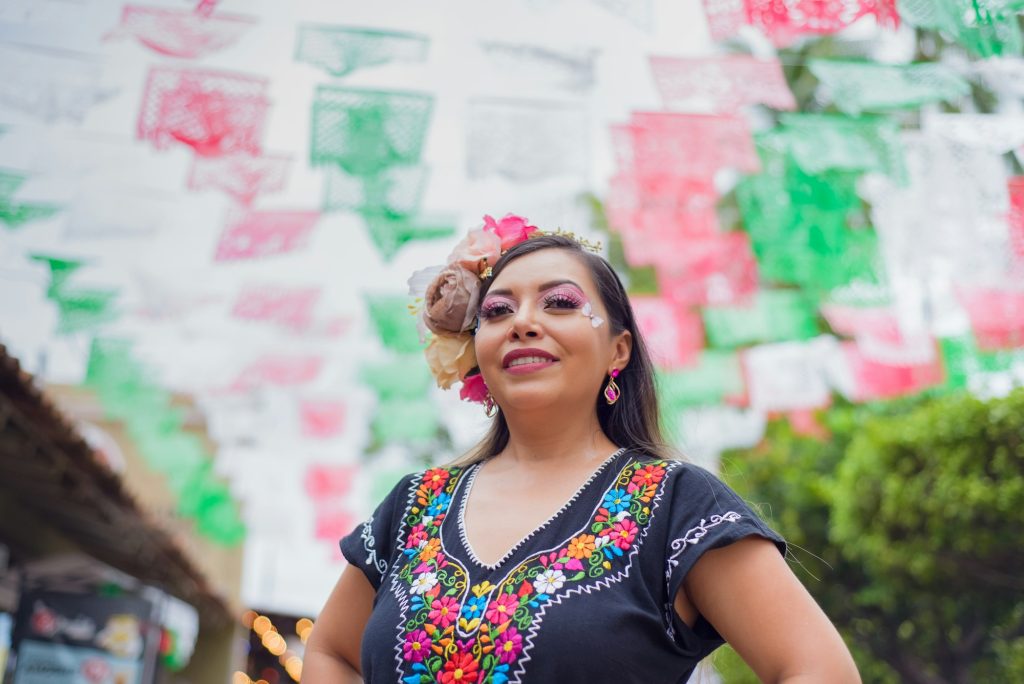 Street portrait of Mexican woman wearing traditional dress with multicolored embroidery.