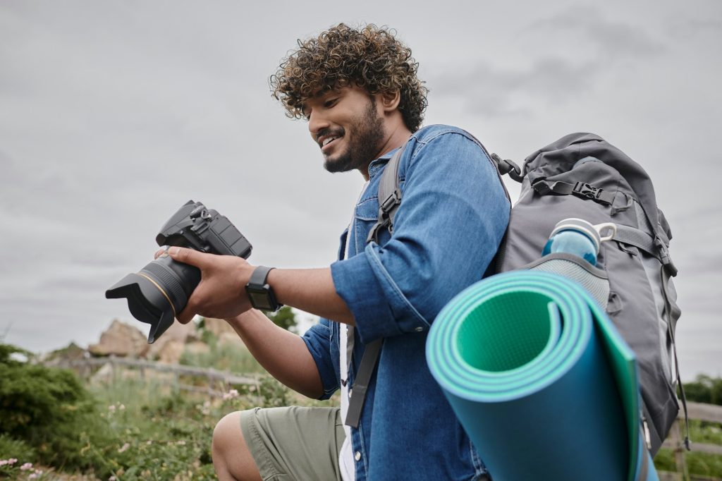 travel photography concept, happy indian backpacker holding digital camera during journey