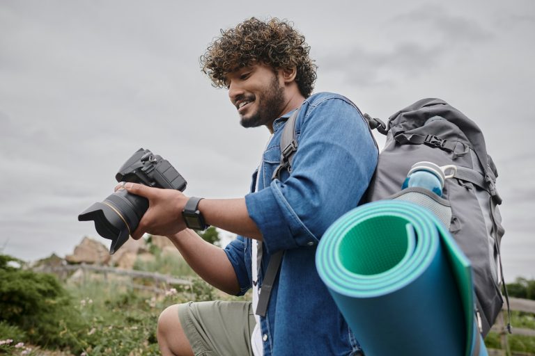travel photography concept, happy indian backpacker holding digital camera during journey
