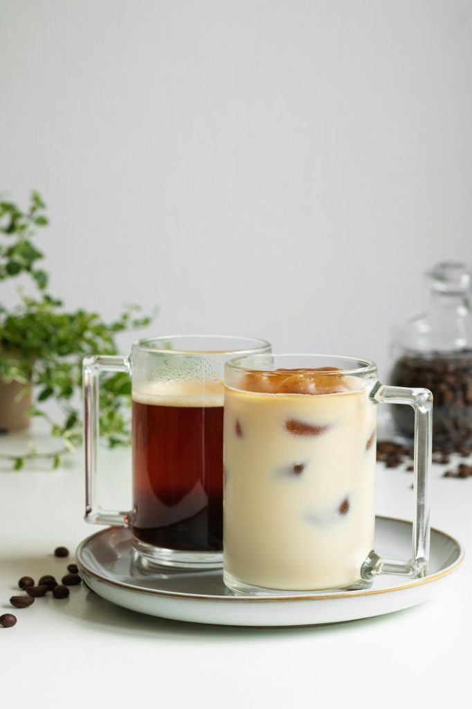 Two cups of coffee. Hot coffee in the background, coffee ice with milk in the foreground.