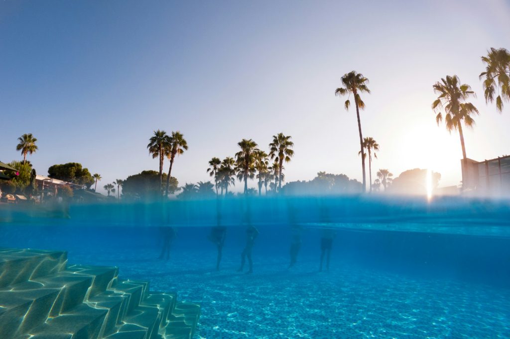 Underwater photography of people standing in pool with copy space. Beach resort vacation by sea