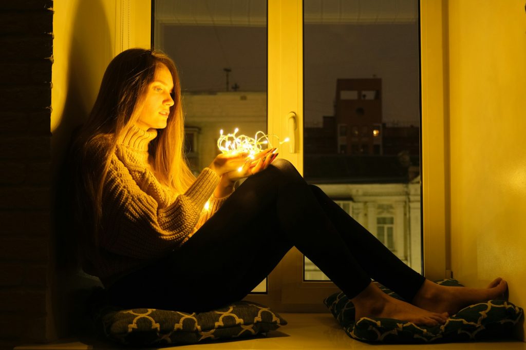 Winter night portrait of young beautiful woman sitting near window