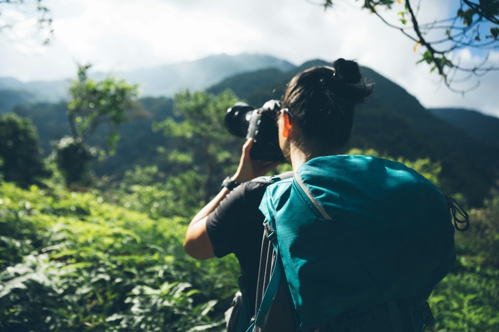 Woman photographer taking pictures in summer mountains