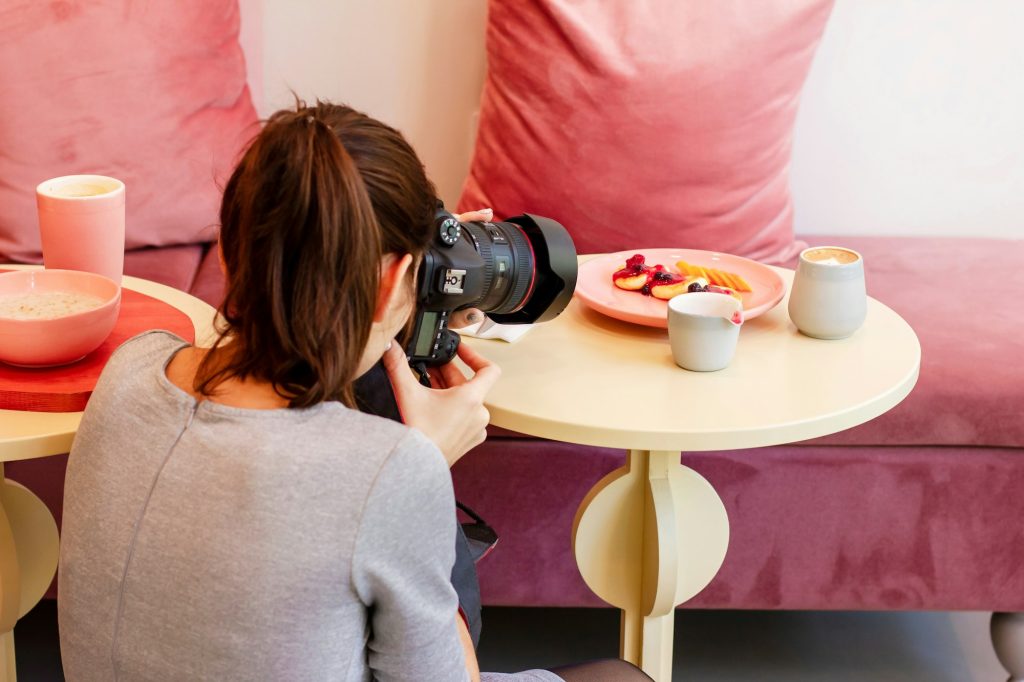 Young woman food photographer shoots Breakfast in cafe